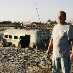 Man stands next to his mobile home in the desert