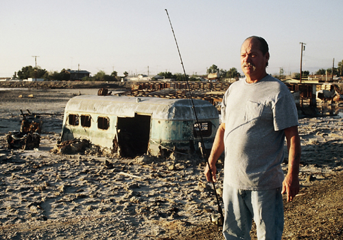 Man stands next to his mobile home in the desert