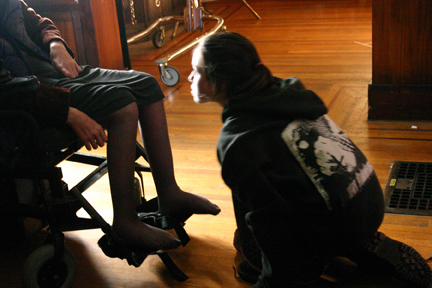 Teenage girl kneeling in front of wheelchair