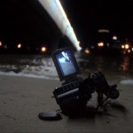 A video camera lies in the sand at the beach at night