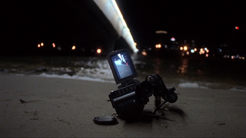 A video camera lies in the sand at the beach at night