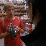 Teenage boy shops for a video camera in a store