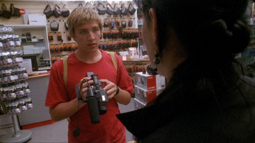 Teenage boy shops for a video camera in a store