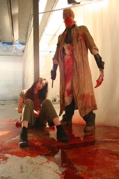 Man in bloody surgical gown stands over dead woman