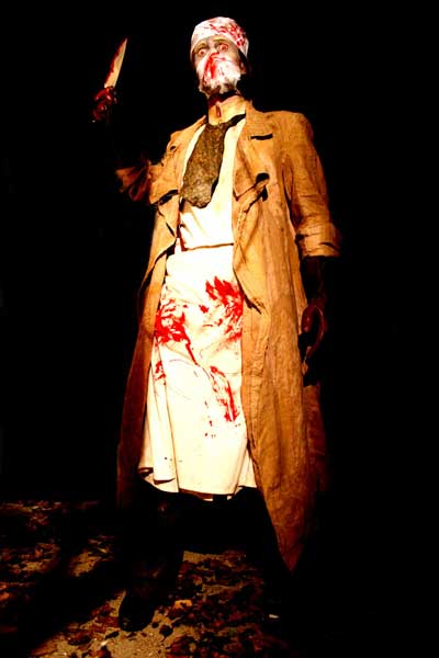 Man in bloody surgical gown holding a butcher knife