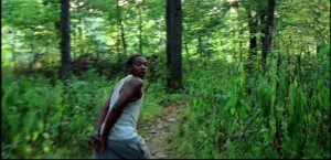 African American teenage boy with his hands tied togethre runs for his life through the woods
