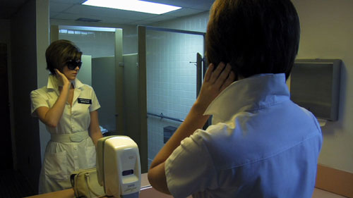 Nurse wearing sunglasses fixes her hair in the mirror