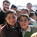 Filmmaker Usama Alshaibi stands with Iraqi children at an outdoor market
