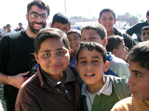 Filmmaker Usama Alshaibi stands with Iraqi children at an outdoor market