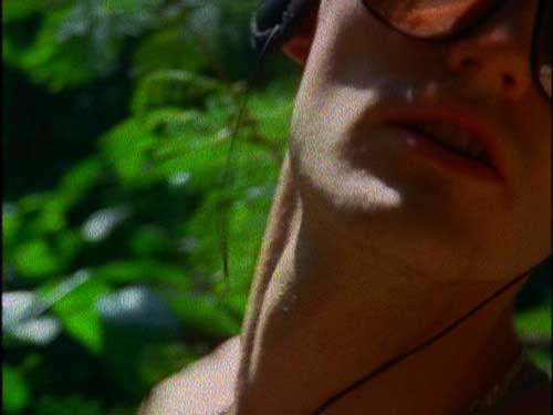 Young man listening to music on headphones in the jungle