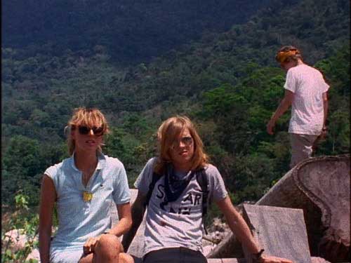 Three young adults hang out on an overlook in the jungle
