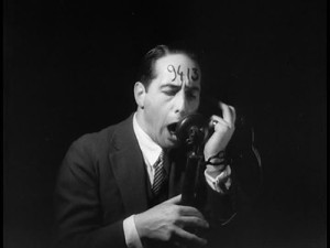 Man with 9413 written on his forehead yells into a telephone