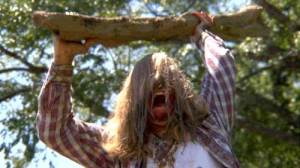 Man with long hair wields branch over his head