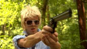Teenage boy with sunglasses pointing a gun