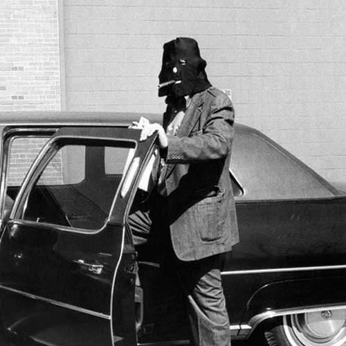 Man wearing black hood getting into car
