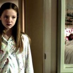 Young girl in pajamas looks in a mirror at the corpse of an older woman