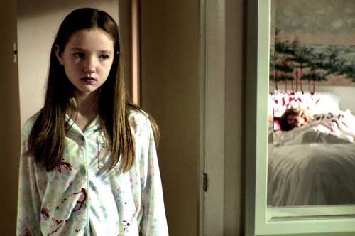 Young girl in pajamas looks in a mirror at the corpse of an older woman