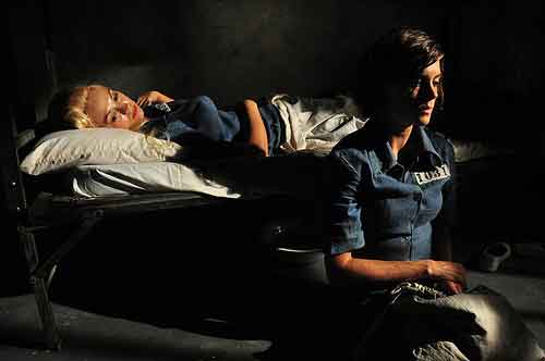 Female prisoner lies in her cot while cellmate sits nearby
