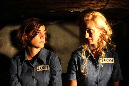 Two pretty female convicts sit in their jail cell
