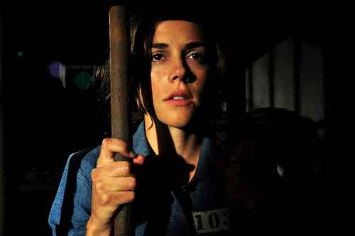 Pretty female prisoner looks out from her jail cell