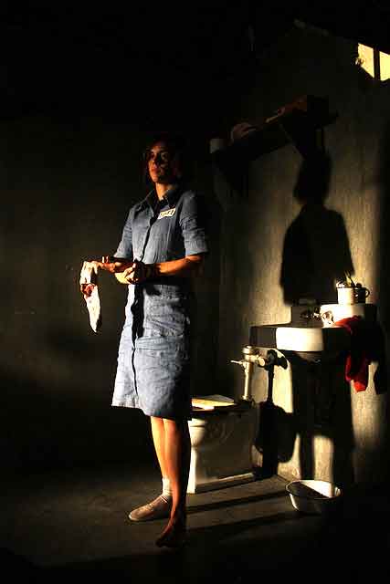 Female prisoner stands by the toilet in her jail cell