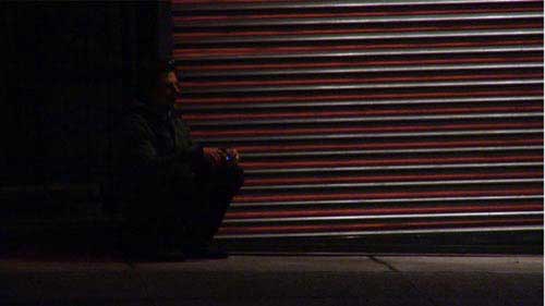 Man sits against a garage door