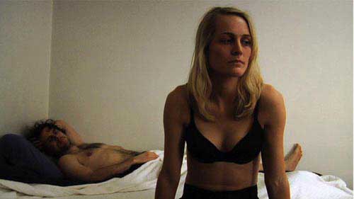 After You Left Man lies in bed while woman in bra looks forlorn