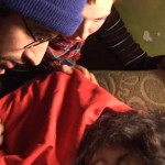 Man wearing winter hat tries to wake up a sleeping woman