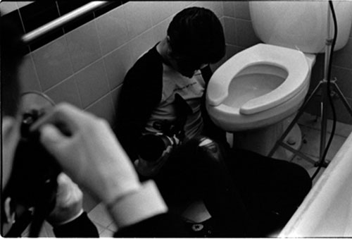 Cinematographer sits on the floor of a bathroom