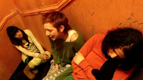 Three woman sit in a stairwell