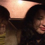 Two women sit close to each other in the backseat of a taxi cab