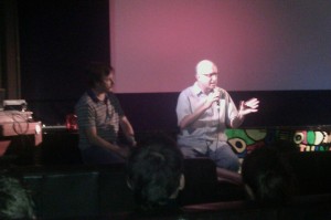 Mike Plante interviews Jeff Krulik on stage of a movie theater