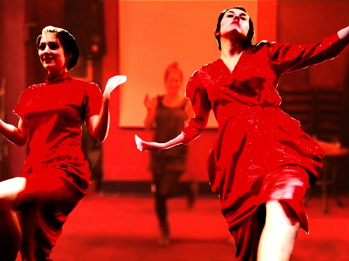 Two teenage girls wearing red dresses perform a modern dance