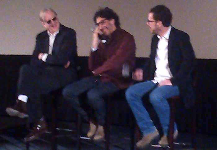 T-Bone Burnett, Joel Coen and Ethan Coen sitting on stage laughing