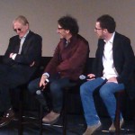 On stage, Joel and Ethan Cohen listen to T-Bone Burnett answer a question