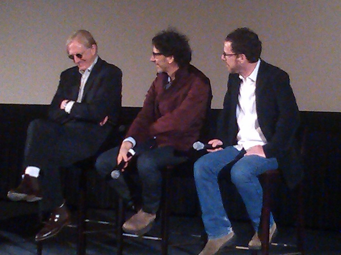 On stage, Joel and Ethan Cohen listen to T-Bone Burnett answer a question