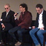 Joel Coen answers a question on stage, flanked by Ethan Coen and T-Bone Burnett