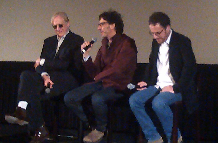 Joel Coen answers a question on stage, flanked by Ethan Coen and T-Bone Burnett