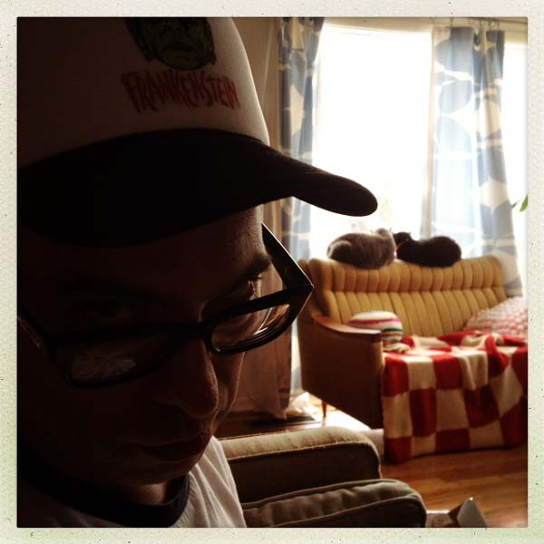 Bob Moricz stares devilishly into the camera while his two cats look out the window in the background