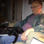 Filmmaker Jeff Krulik tries to work on his laptop while his black cat Iggy sleeps on his legs