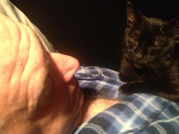 Filmmaker Jeff Krulik is sleeping while his black cat Iggy Smalls lays on his chest.