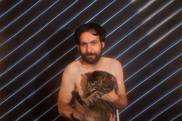 Naked Mike Olenick cradles his striped cat Crystal