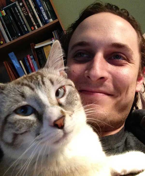 Aaron Zeghers relaxes with his white and gray cat Baby on his chest