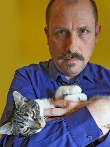 British filmmaker Duncan Reekie cradles his striped cat Tikky in his arms.