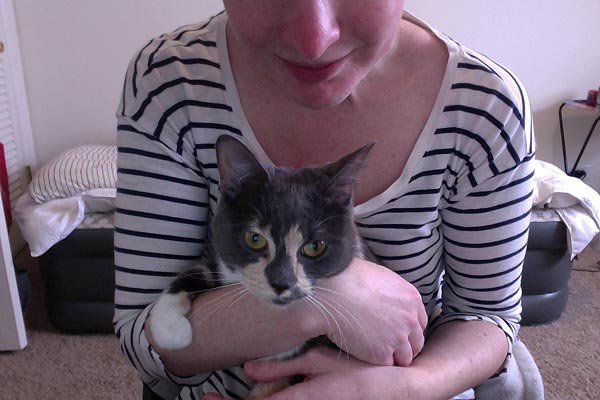 Kate Balsley cradles her grey and white cat Princess in her arms
