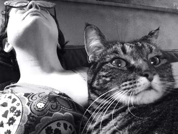 Lisa Barcy leans back on her couch while her cat Nellie rests on Lisa's stomach in this black and white photograph
