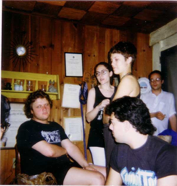 Bunch of people sitting and standing around a cramped indoor film set