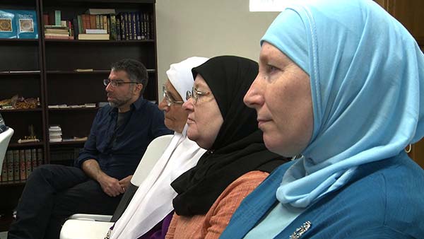 Usama Alshaibi sits in a row with Arab women wearing their hijab