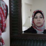 Amal Abusumayah wearing her hijab looks in the mirror