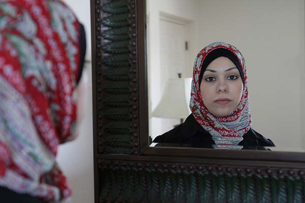 Amal Abusumayah wearing her hijab looks in the mirror